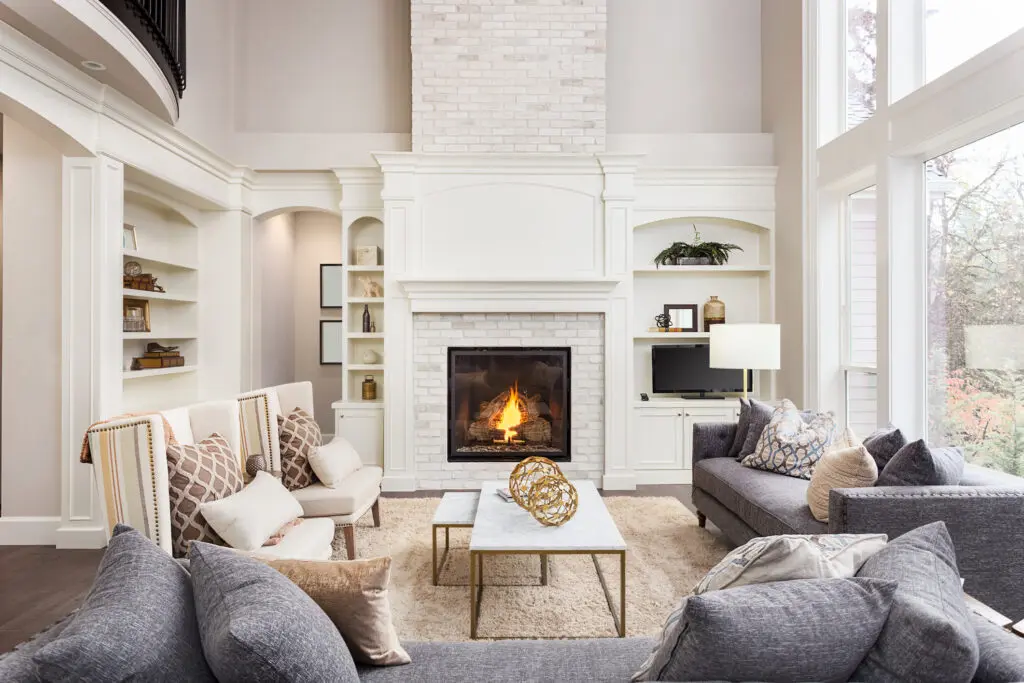 Beautiful living room interior with tall vaulted ceiling, loft area, hardwood floors and fireplace in new luxury home. Has large bank of windows fireproof paint in home interior