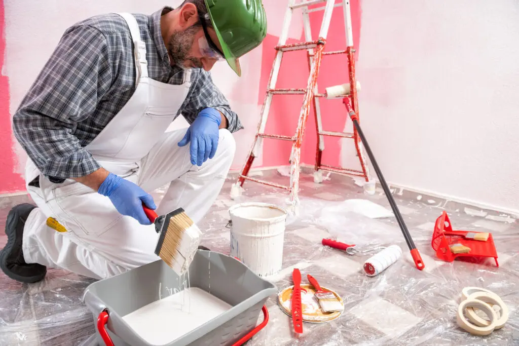 House painter worker at work in the construction site. Building. hiring a painter- exterior paint types